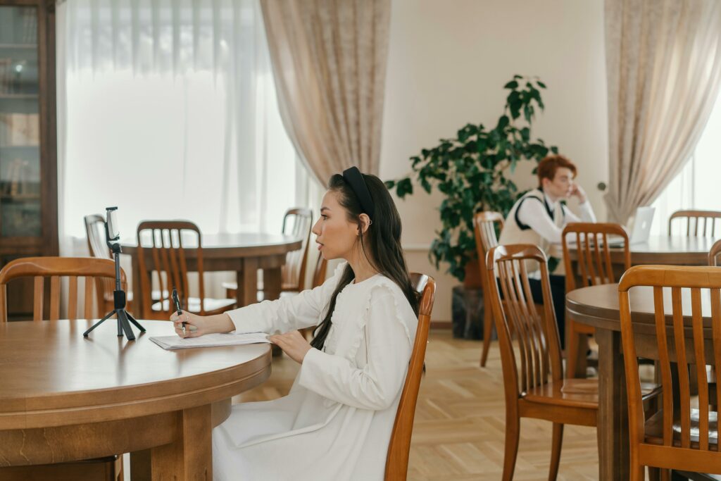 Woman recording video with notes at well-lit table