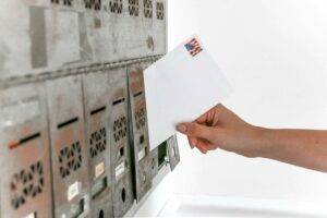 Person holding an envelope in a post office mailbox representing EDDM for Realtors and real estate agent marketing