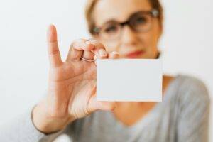 Woman holding business cards for real estate agents and realtors in 2025
