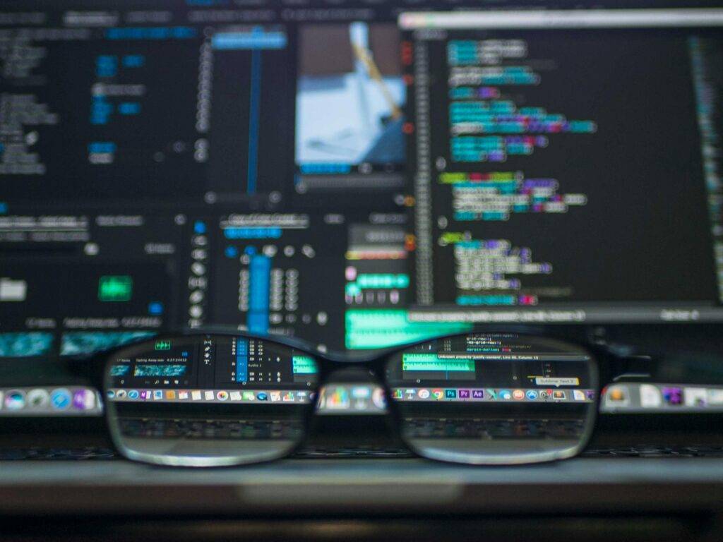 A pair of eyeglasses in front of complex computer screens representing data in real estate advertising.