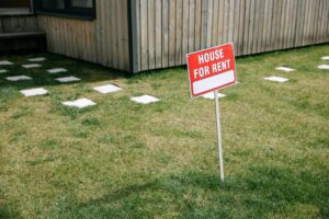 Front yard with ‘house for rent’ sign representing the property of an absentee home owner for real estate agent marketing