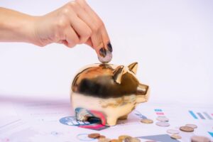 Person putting coin into a piggy bank representing real estate marketing ROI and effective budget management for realtor homebuyer and seller lead generation
