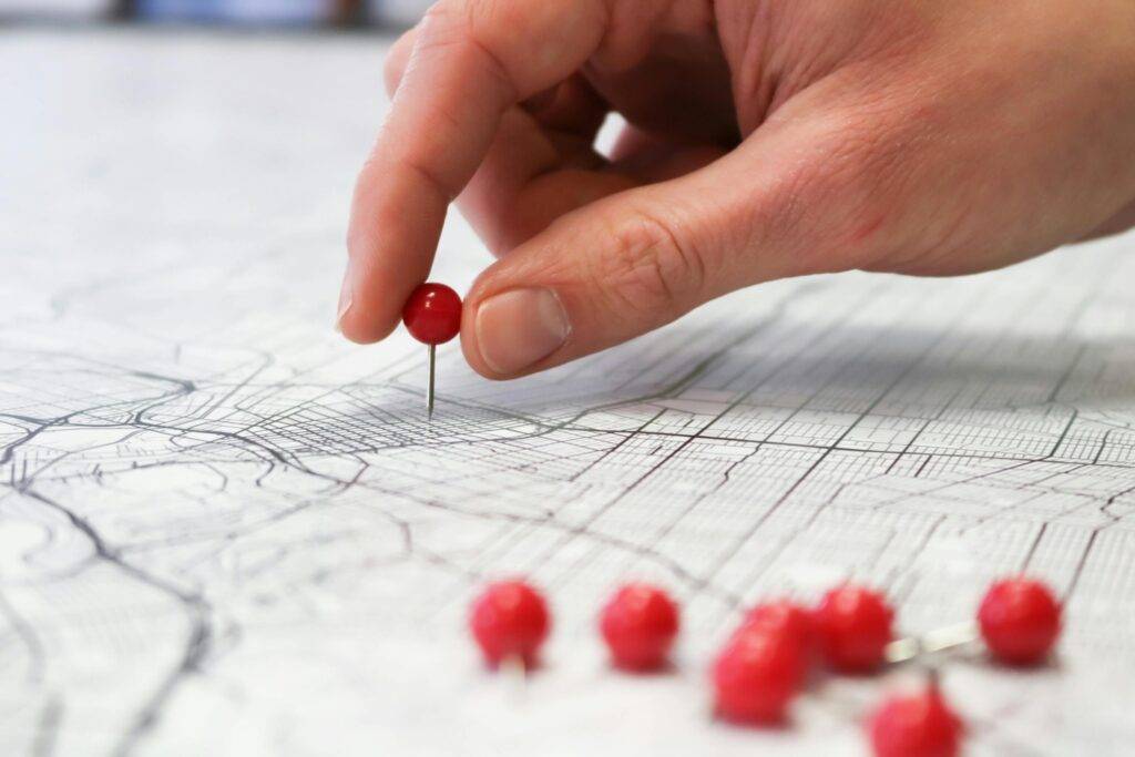 Hand places pin on a map to represent targeted local neighborhood real estate marketing
