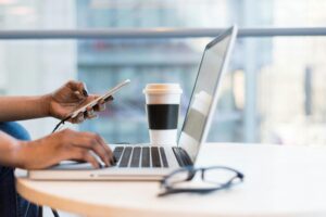 Woman’s hand on a laptop at a cafe, representing digital marketing for real estate agents