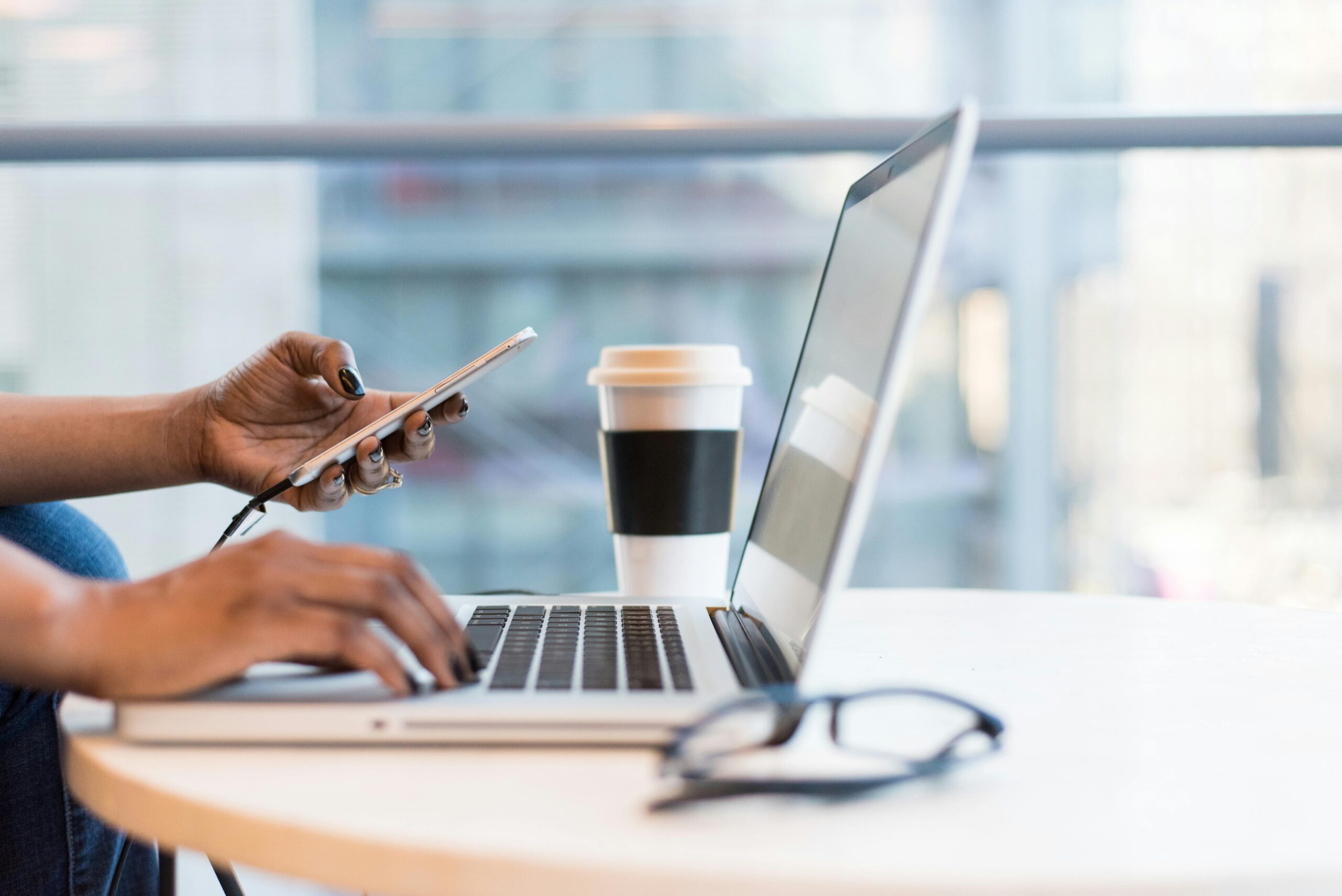 Woman’s hand on a laptop at a cafe, representing digital marketing for real estate agents