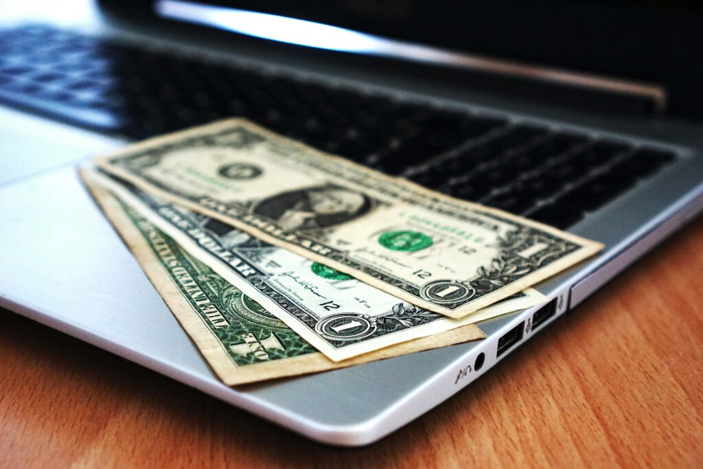 A few dollar bills sitting on a laptop, representing the dollar a day advertising strategy
