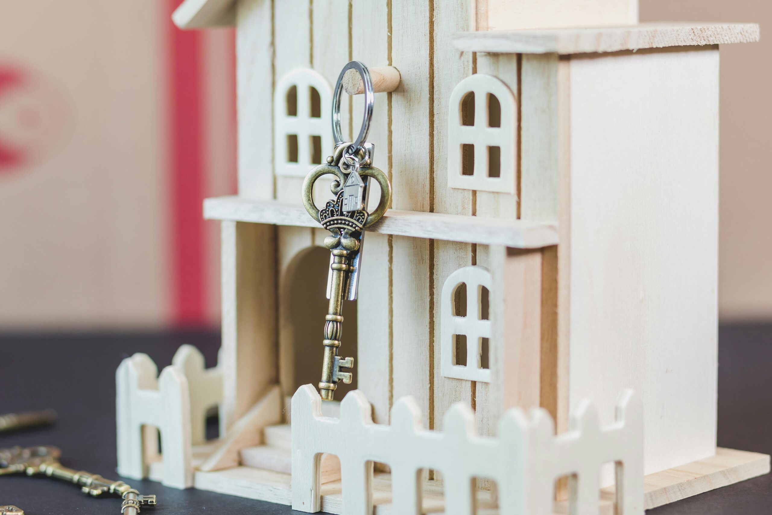 Key hanging on a wooden doll house, representing the best agent marketing for real estate leads from hot to cold buyers and sellers