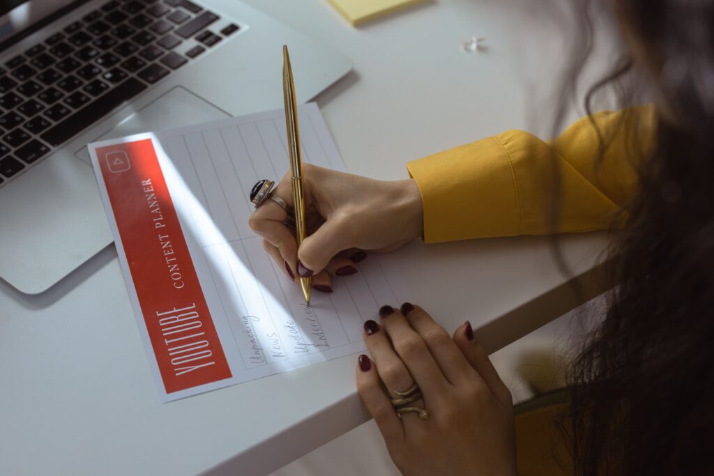 Woman writing on a paper for YouTube content planning ahead which helps real estate agents stay consistent with social media post marketing for lead generation