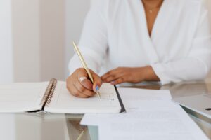 Person at a desk writing in a planner, working on their real estate marketing strategy for agents to grow their business and win more buyer and seller leads generation
