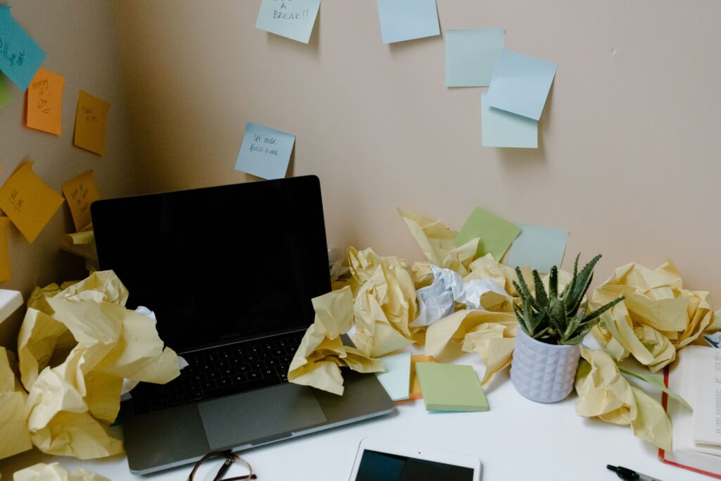 Cluttered desk with crumpled paper, representing the chaos of a busy real estate agent realtor’s schedule which is bad for new lead gen and effective buyer and seller marketing tactics.