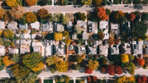 Aerial view of a tree-lined suburban neighborhood in fall, with rows of homes between two streets, a possible real estate farming area